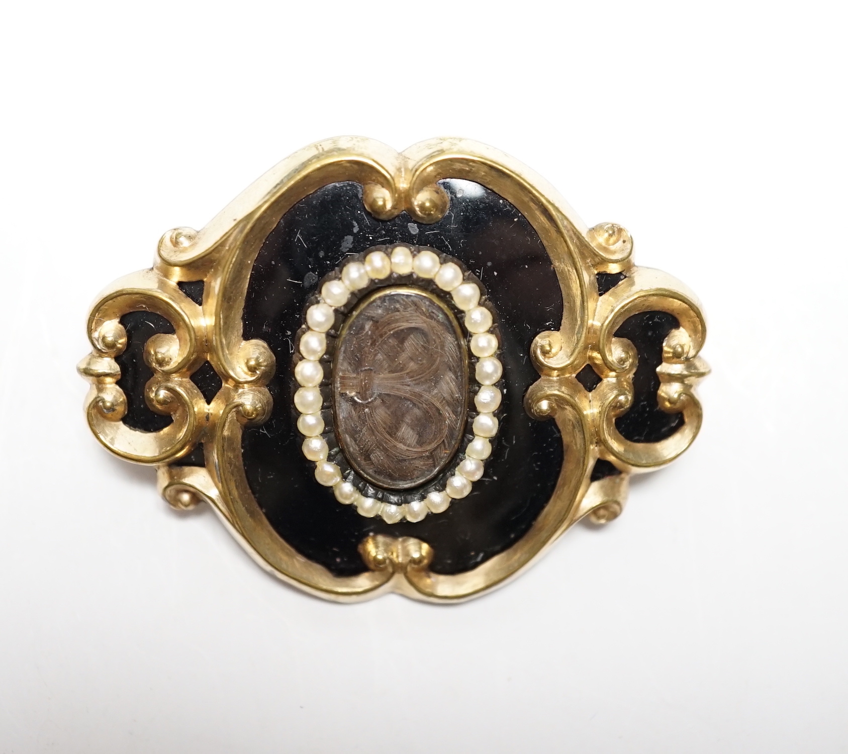 A Victorian yellow metal, black enamel and seed pearl set mourning brooch, 47mm.
